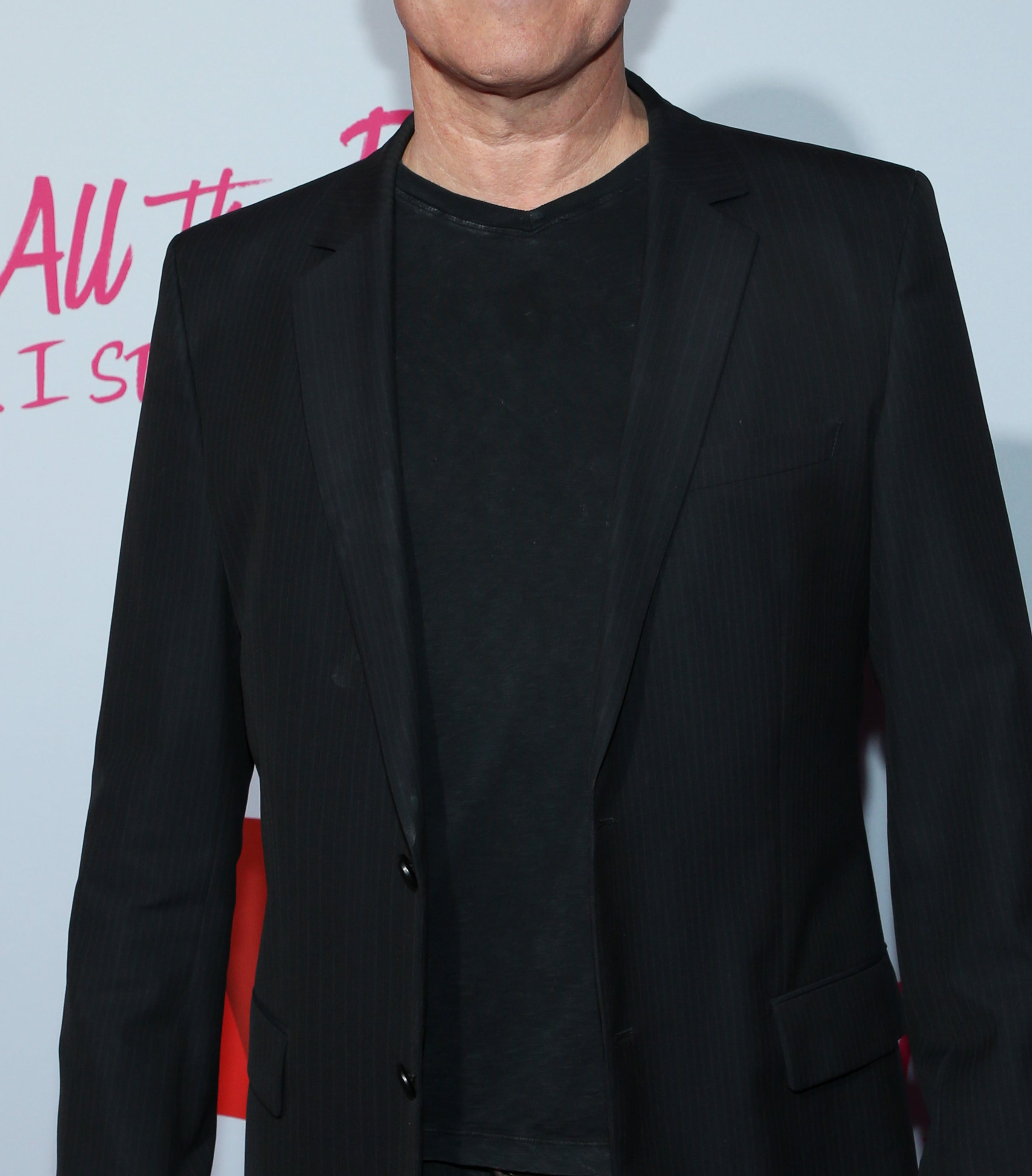 John Corbett stands on the red carpet in a black suit jacket over a black t-shirt at the &quot;To All The Boys: P.S. I Still Love You&quot; premiere event