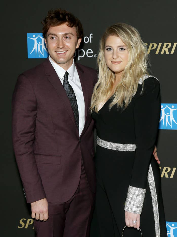 Daryl Sabara in a suit and Meghan Trainor in a dress with silver accents at a celebrity event