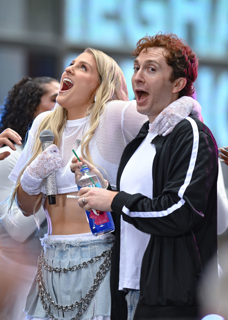 Meghan Trainor, in a crop top and chain accents, and Chris Olsen, in a track jacket, perform energetically together on stage