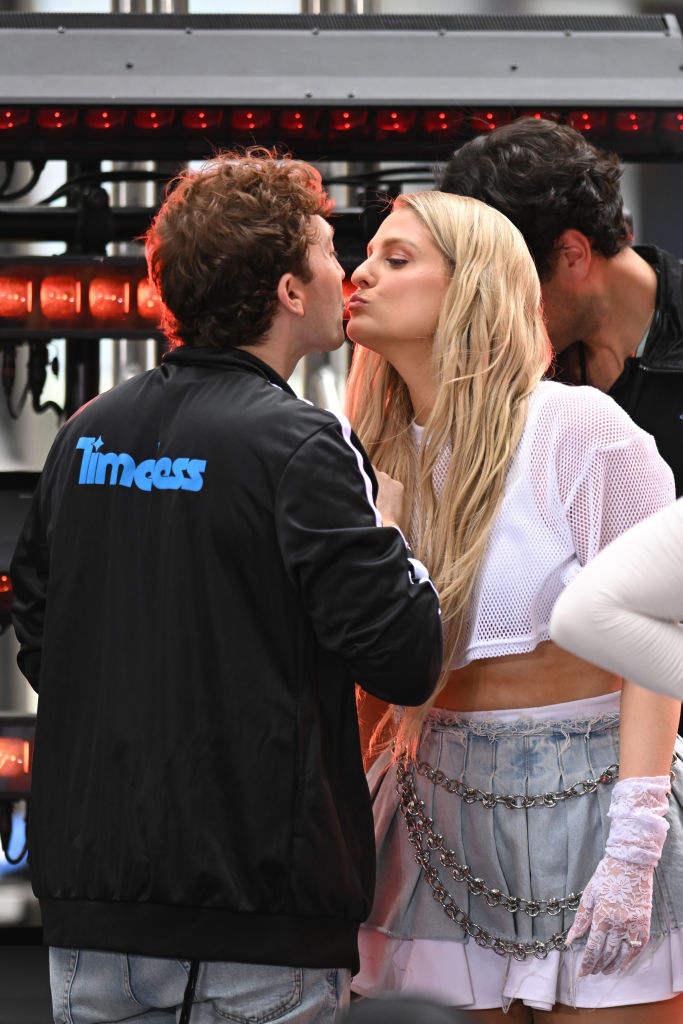 Daryl Sabara kisses Meghan Trainor wearing a mesh top and chain-adorned skirt on stage