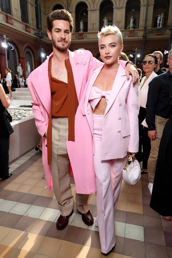 Andrew Garfield and Florence Pugh at an event, both dressed in stylish, light-colored suits