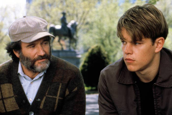 Robin Williams and Matt Damon sitting on a park bench, having a serious conversation. Statue in the background
