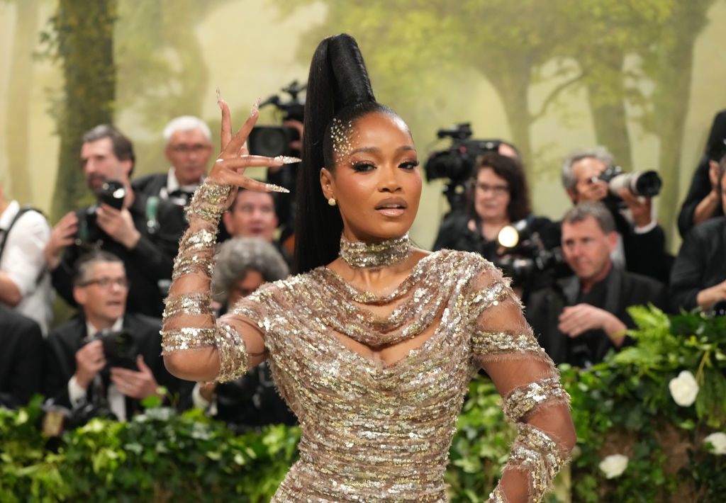 Keke Palmer strikes a confident pose on the red carpet, wearing an elegant, shimmering gown with intricate embellishments, surrounded by photographers