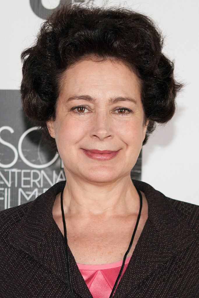 Sean Young attends an event, wearing a blazer over a pink top and smiling at the camera