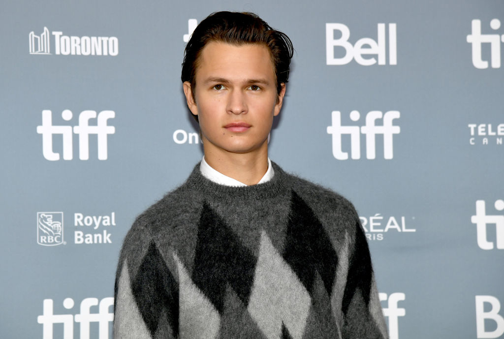 Ansel Elgort at a TIFF event, dressed in a diamond-patterned sweater with a collared shirt underneath