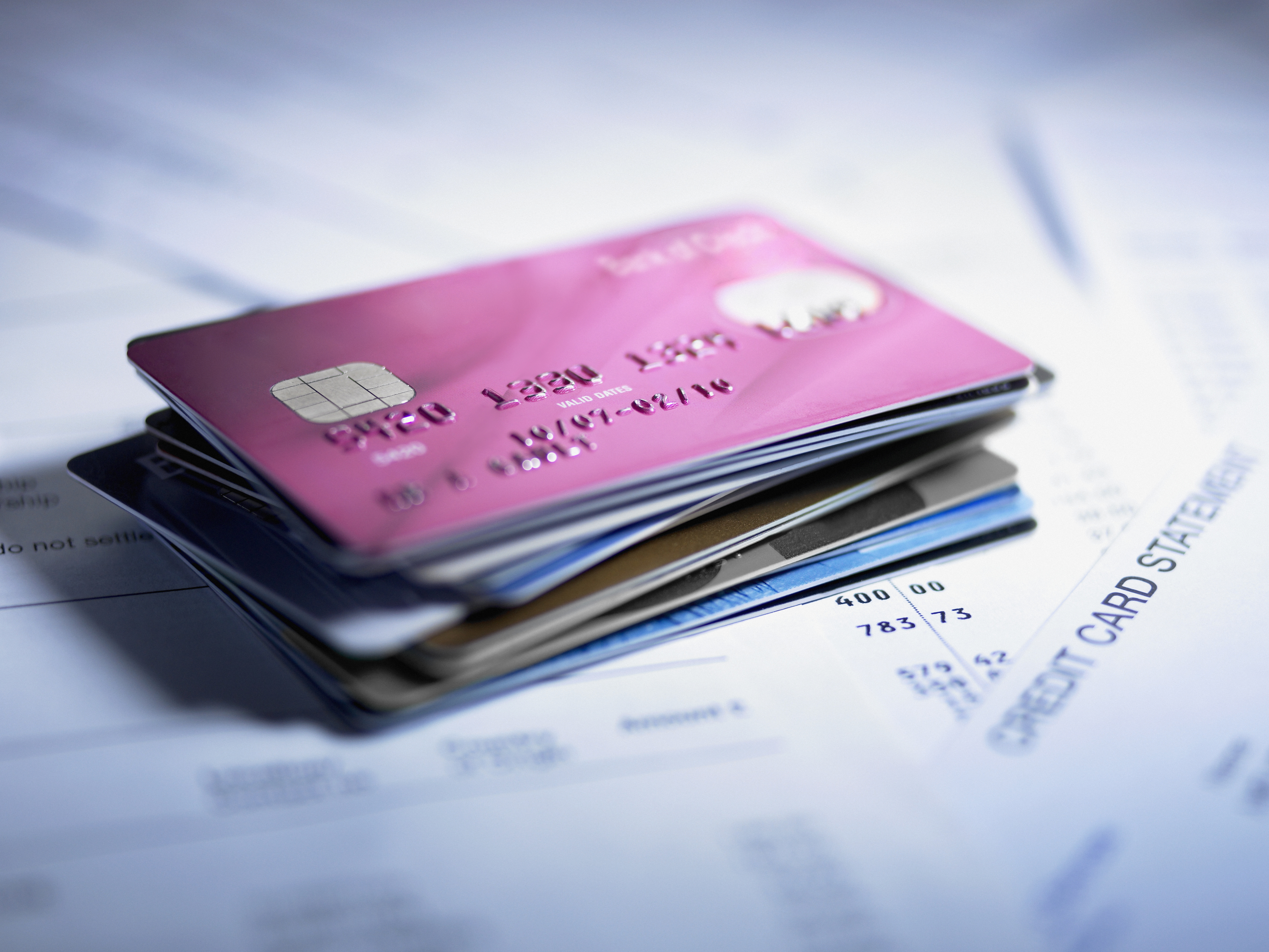 A stack of credit cards placed on top of various financial documents