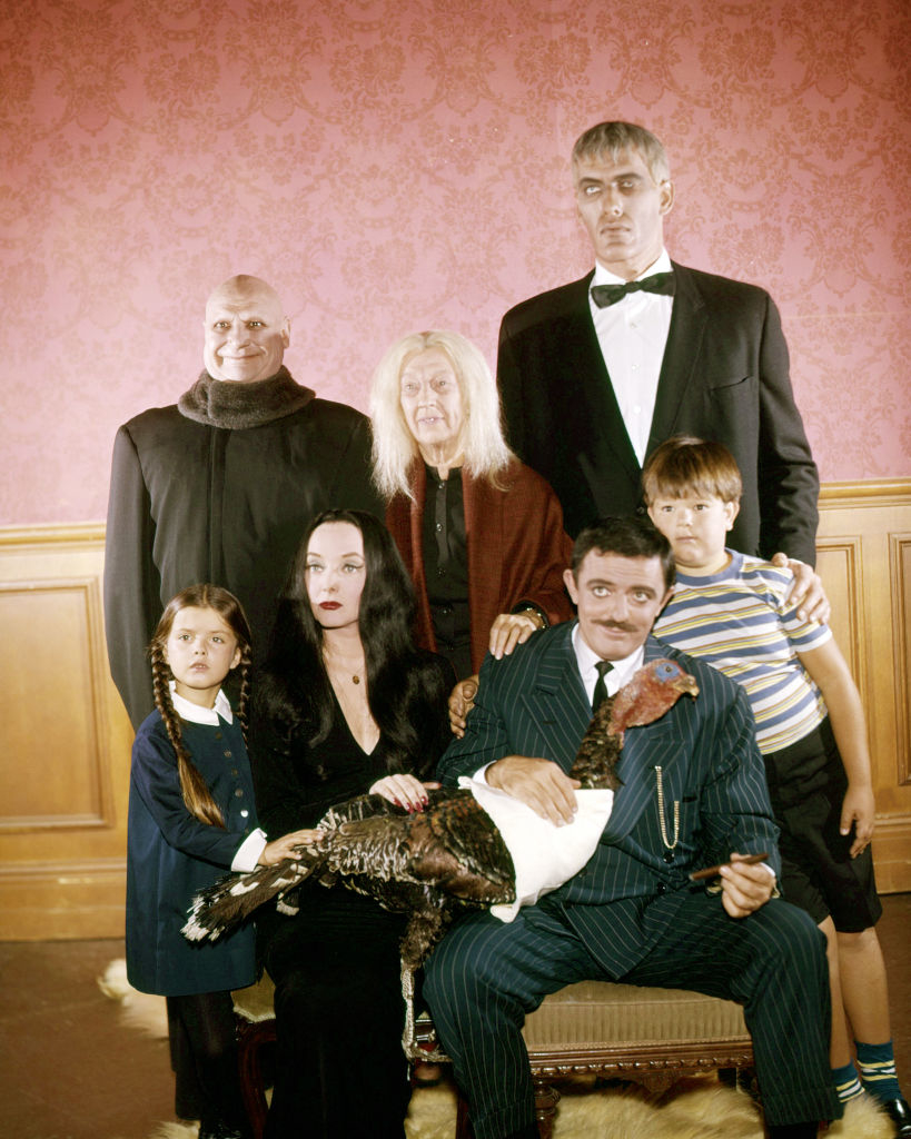 The image features characters Uncle Fester, Grandmama, Lurch, Wednesday, Morticia, Gomez, and Pugsley from &quot;The Addams Family&quot; TV show, posing with a turkey