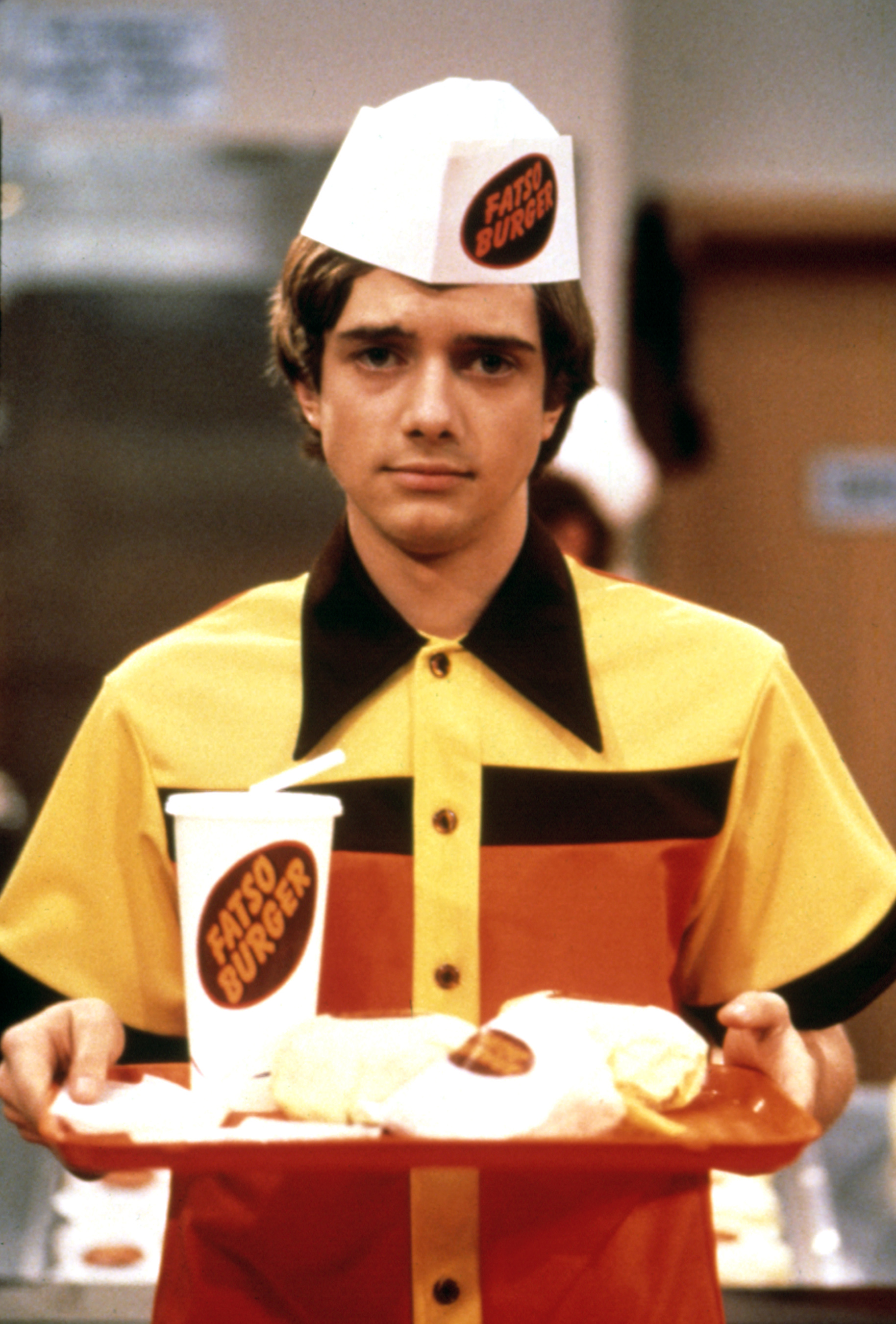 Eric wearing a &quot;Fatso Burger&quot; uniform holds a tray with fast food items