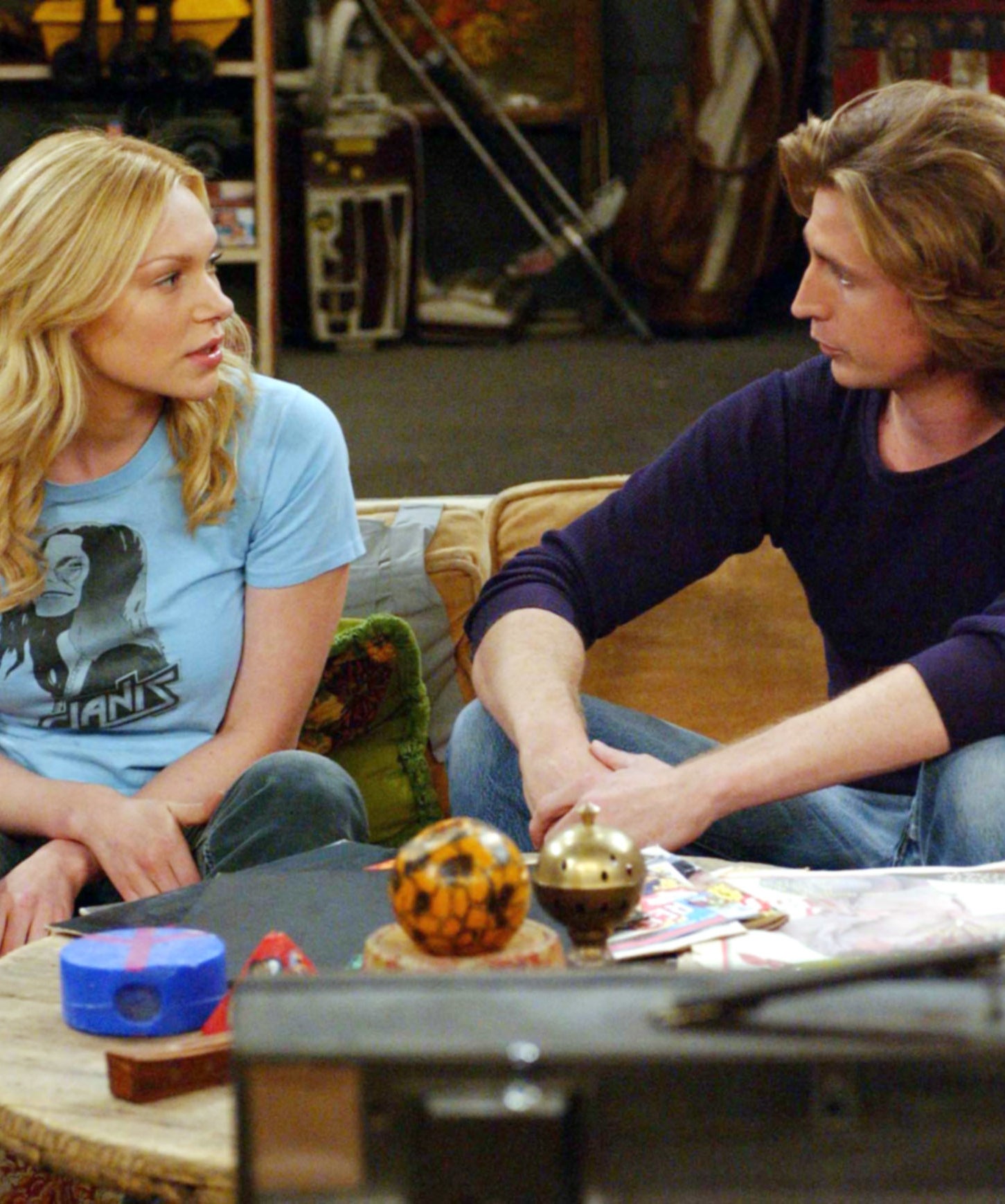 Randy sitting on a couch, talking, with various items on a coffee table in front of him