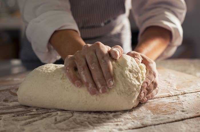 Hands kneading dough on a floured surface