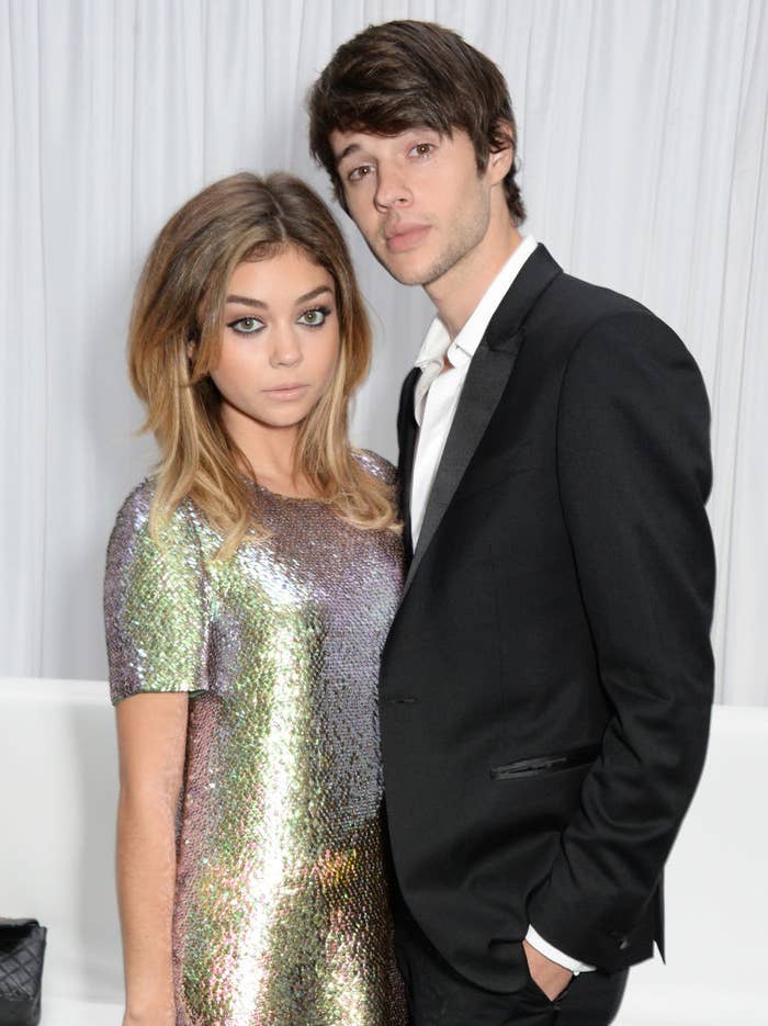 Sarah Hyland in a sparkly dress and Matt Prokop in a blazer pose together against a simple backdrop