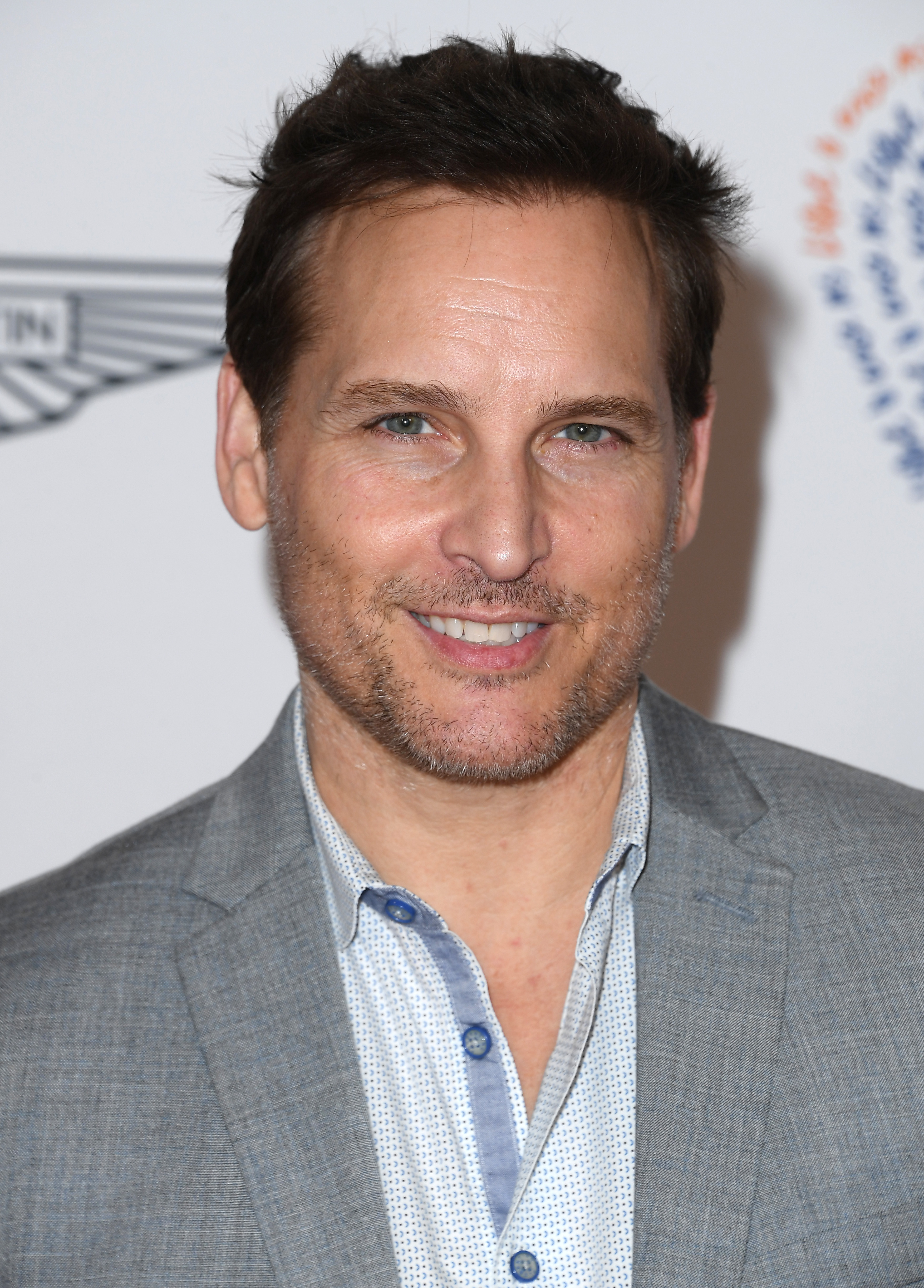 Peter Facinelli at a red carpet event, wearing a light grey blazer over a patterned shirt