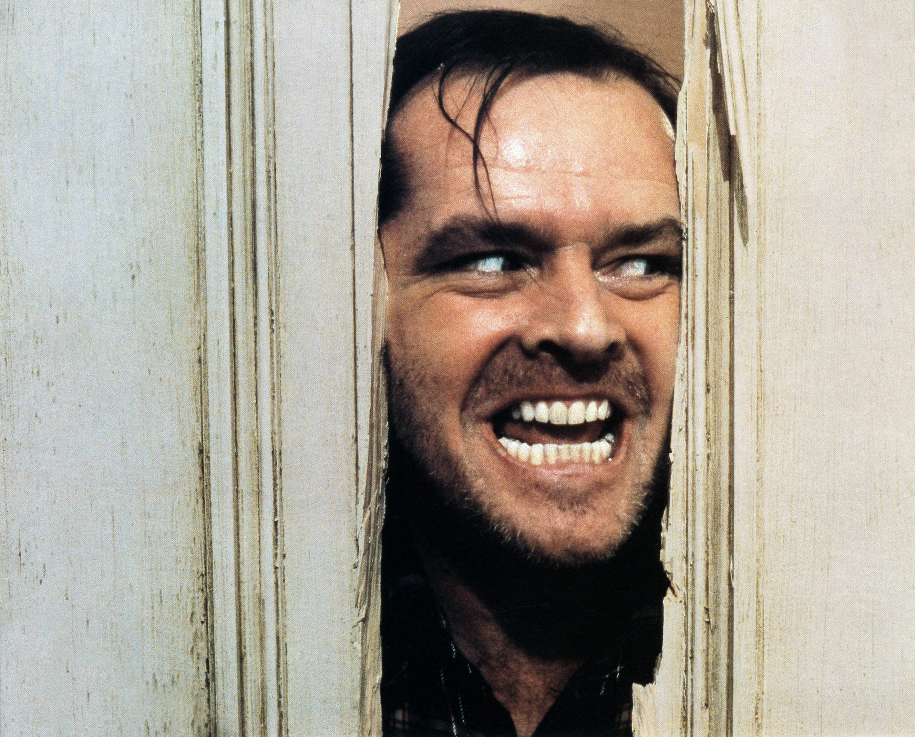 Jack Nicholson peers through a broken door with a manic expression, reenacting a famous scene from &quot;The Shining.&quot;