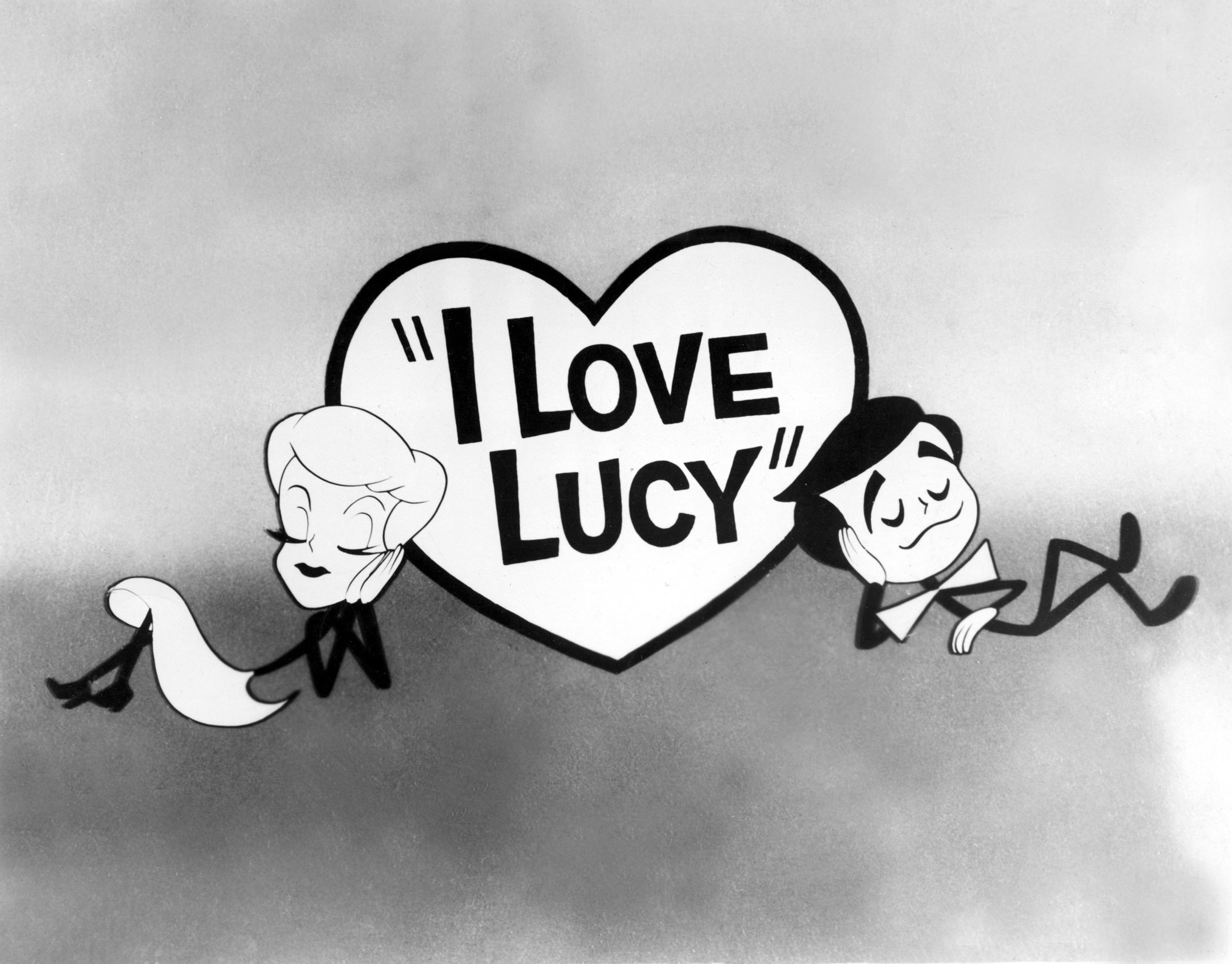 Cartoon characters of Lucille Ball and Desi Arnaz lean against a heart with &quot;I Love Lucy&quot; written inside