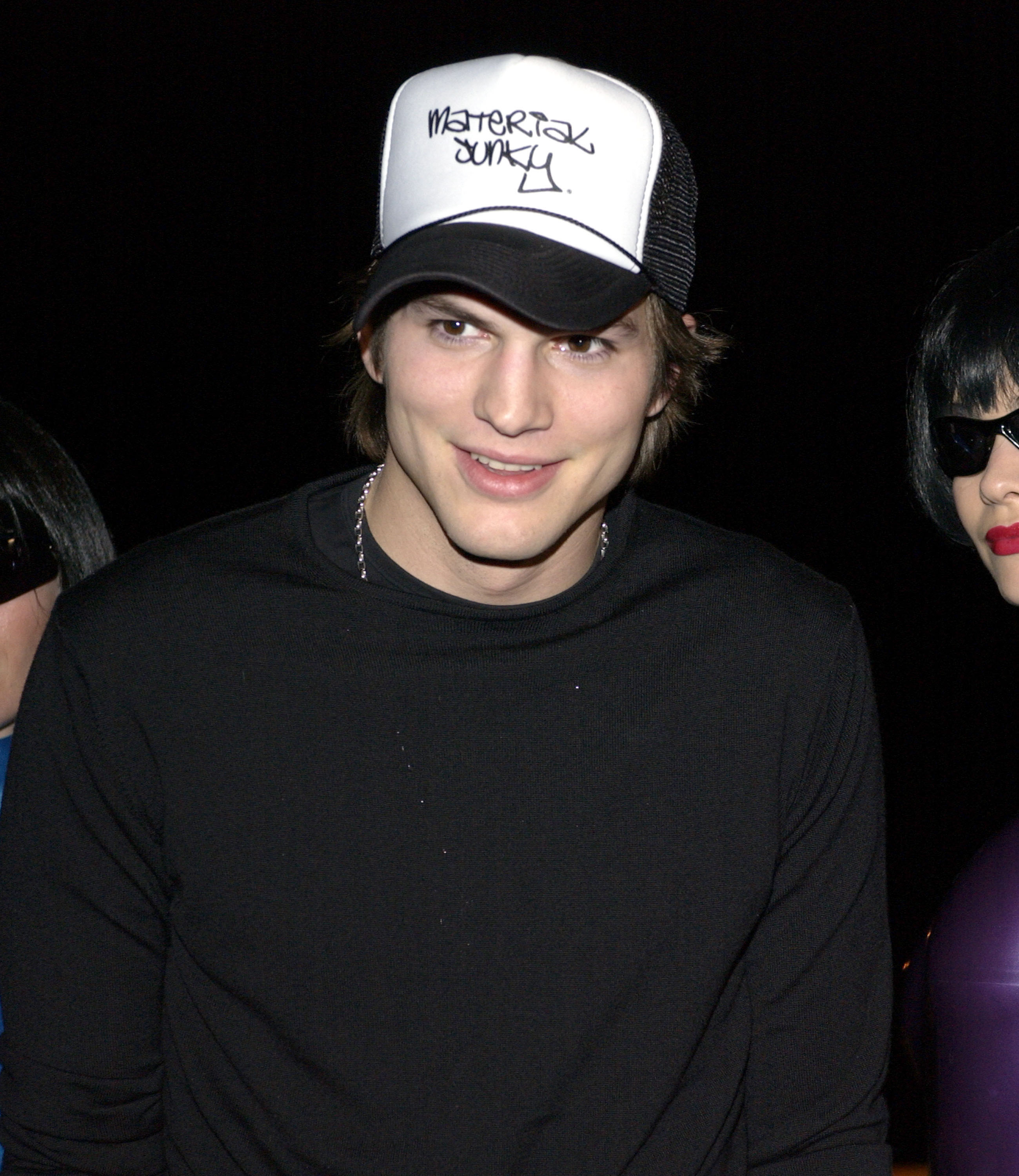 Ashton Kutcher wearing a trucker style baseball cap with &quot;Material Junky&quot; written on it