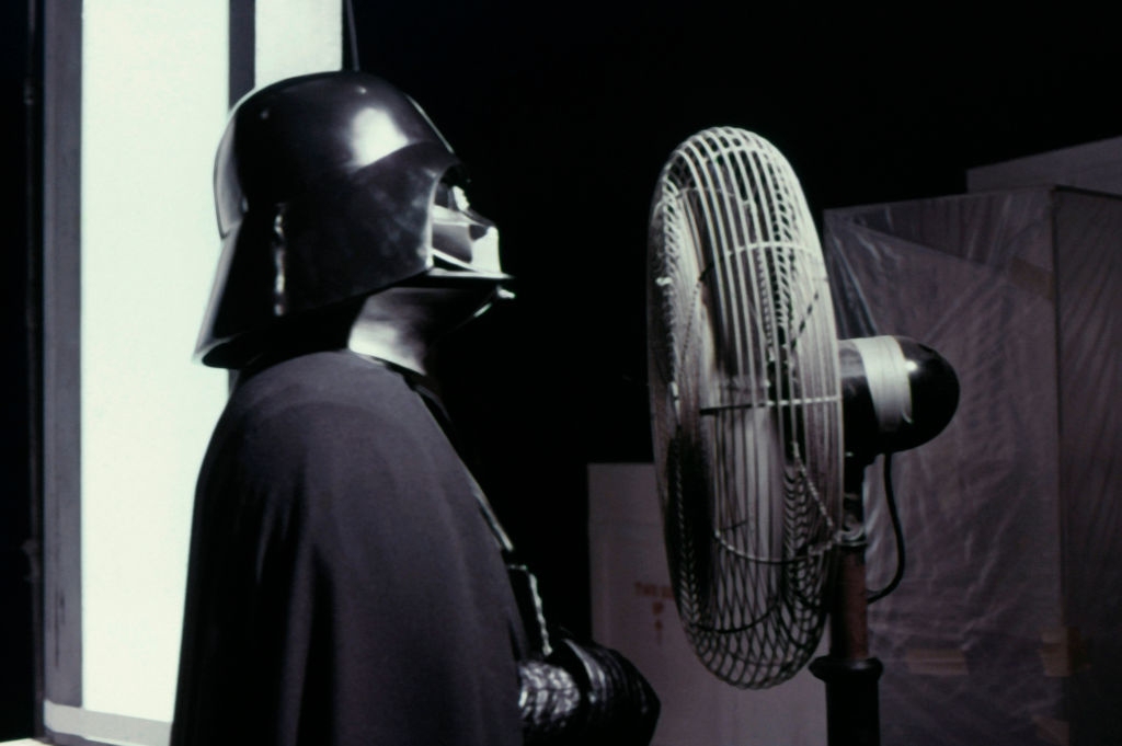 Darth Vader, a character from Star Wars, standing in front of a fan on set