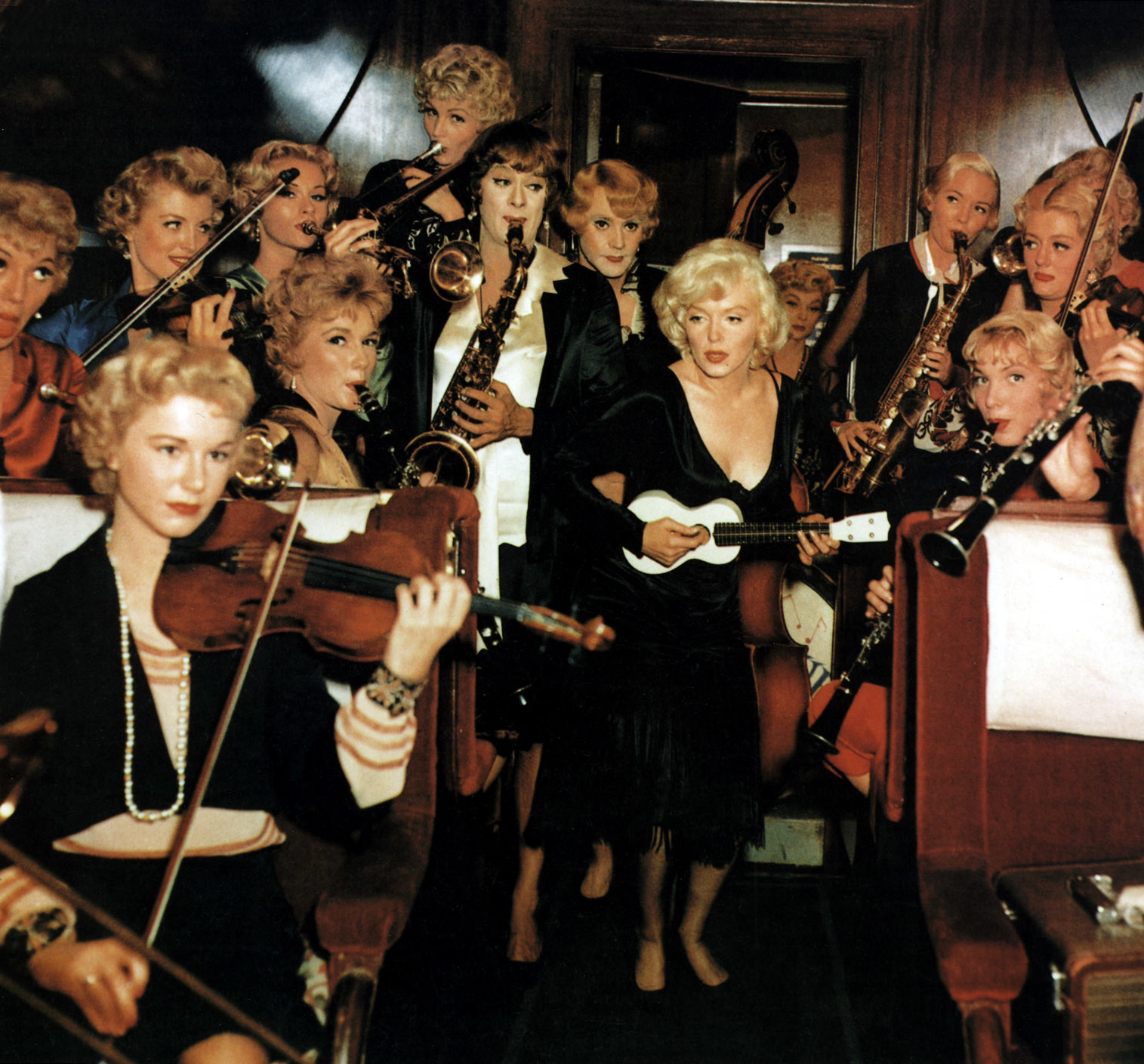 Marilyn Monroe playing a ukulele surrounded by a group of women musicians playing various instruments in the movie &quot;Some Like It Hot.&quot;