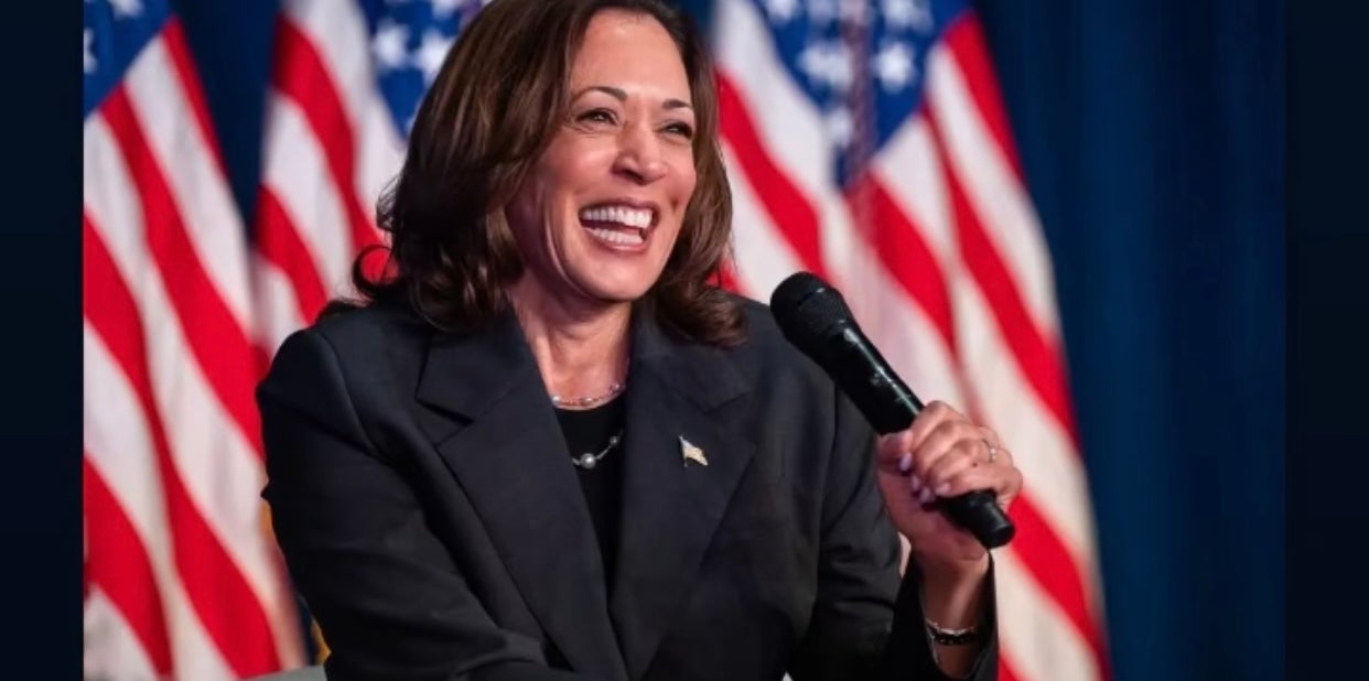 Vice President Kamala Harris seated, smiling, holding a microphone, with American flags in the background. Text: &quot;Ready for Madam Vice President.&quot;