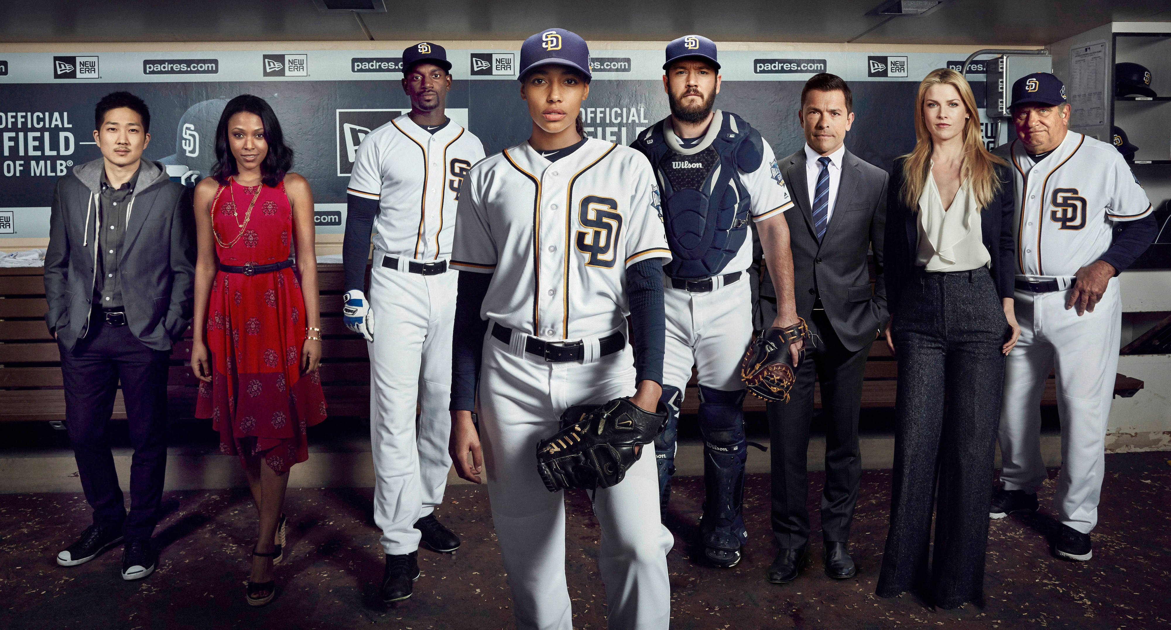 Actors dressed as a baseball team stand in a dugout with two others in formal attire. Characters from &quot;Pitch&quot;: Ginny, Mike, Amelia, Blip, Evelyn, Oscar, Al