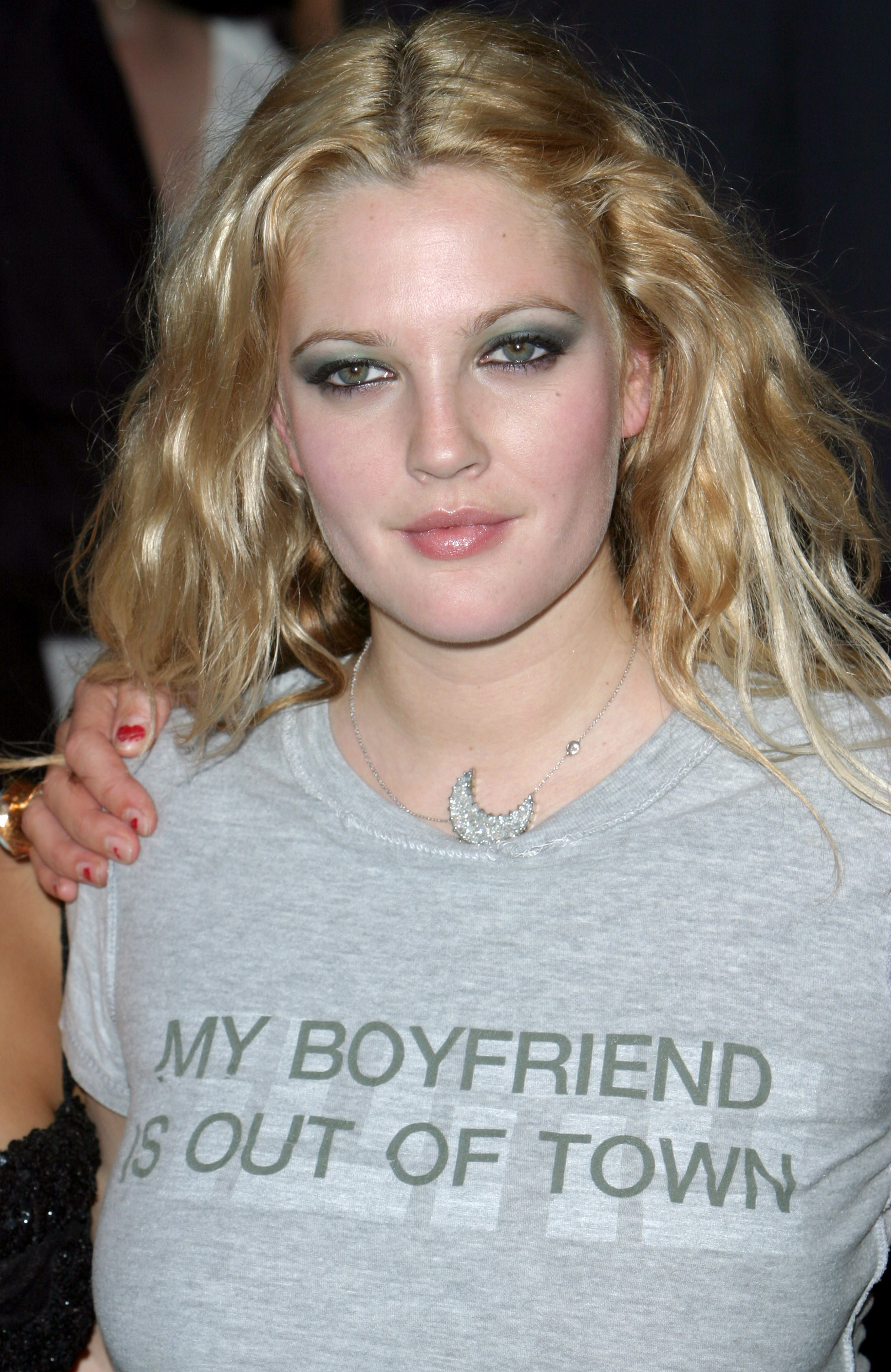 Drew Barrymore poses with a slight smile, wearing a shirt that reads “MY BOYFRIEND IS OUT OF TOWN.”
