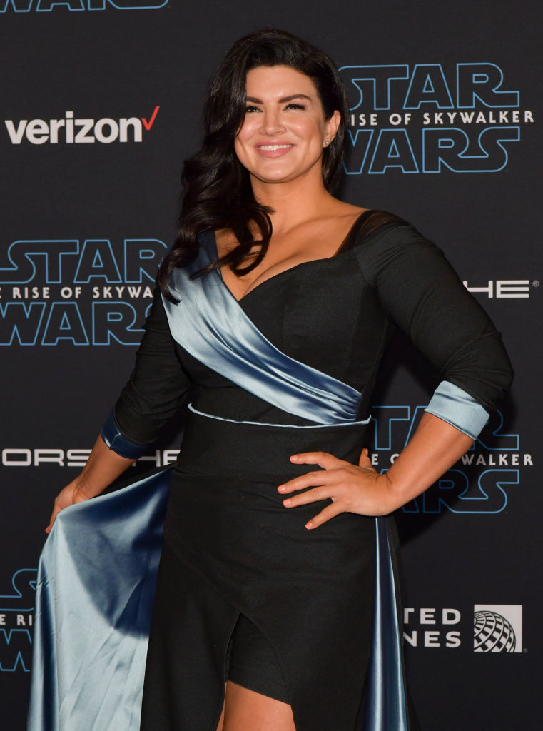 Gina Carano at the &quot;Star Wars: The Rise of Skywalker&quot; premiere, wearing a black dress with a satin blue sash and asymmetrical design