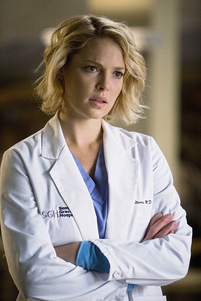 Katherine Heigl as Dr. Izzie Stevens in &quot;Grey&#x27;s Anatomy,&quot; wearing a white doctor&#x27;s coat with folded arms, looking concerned