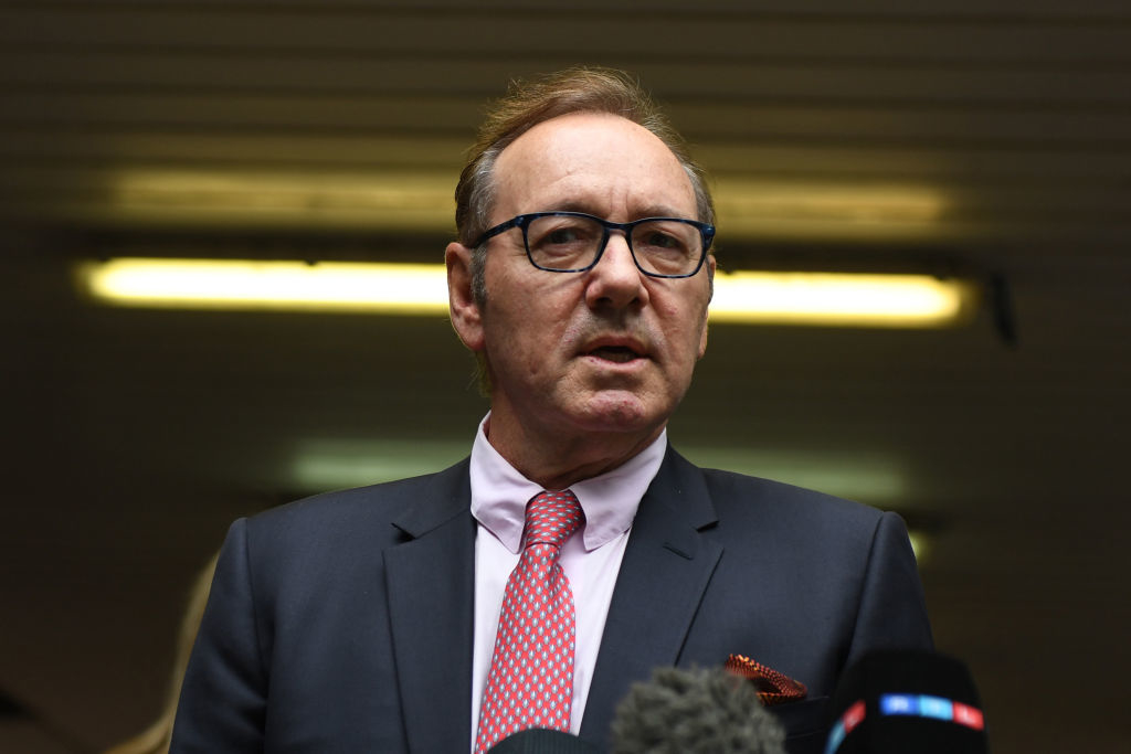 I don&#x27;t know who this is. A man in a suit and tie stands in front of some microphones, giving a speech or interview