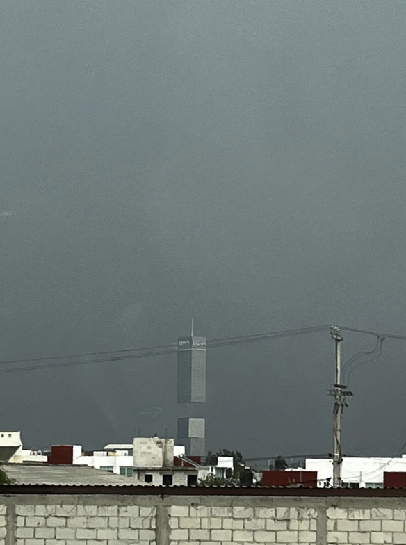 A tall, narrow structure with the word &quot;OMA&quot; at the top is seen from a distance amidst a gray sky and urban foreground