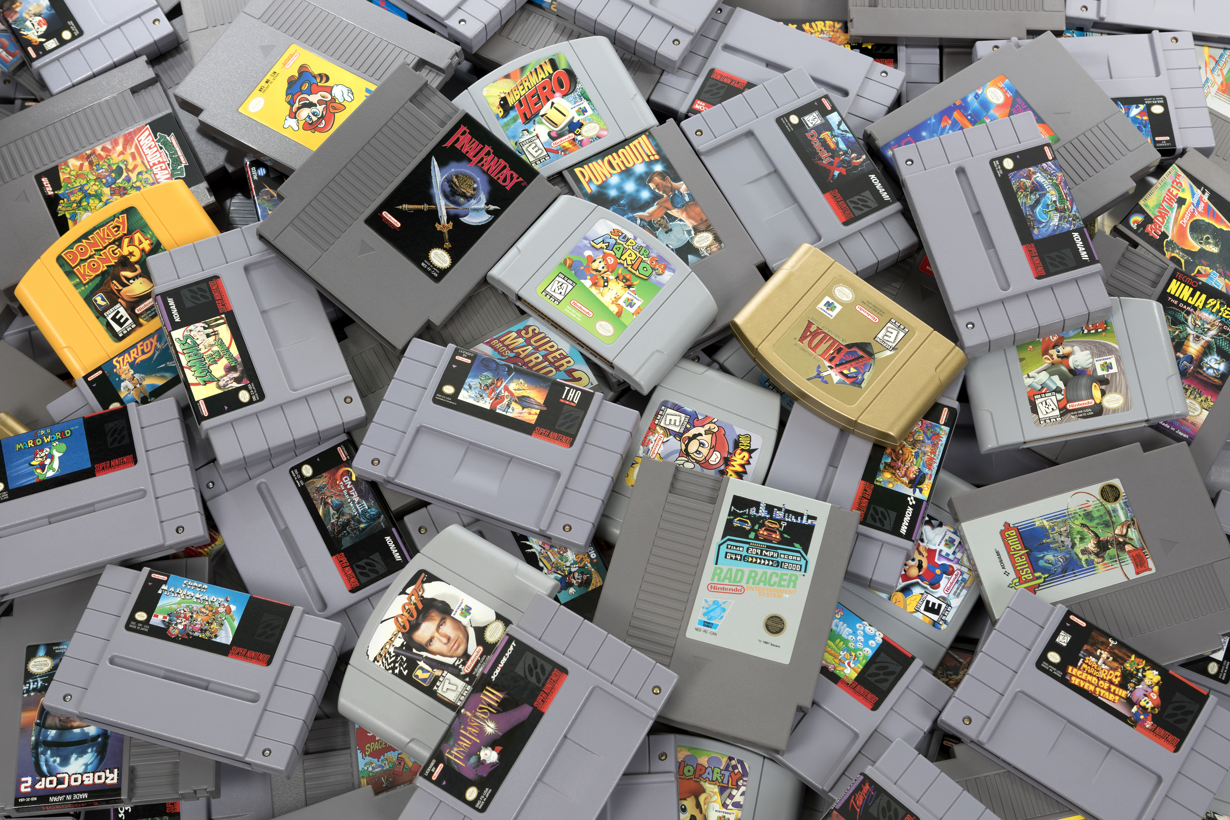 A large pile of various retro video game cartridges from the 1990s, including titles like Super Mario, Zelda, and Donkey Kong