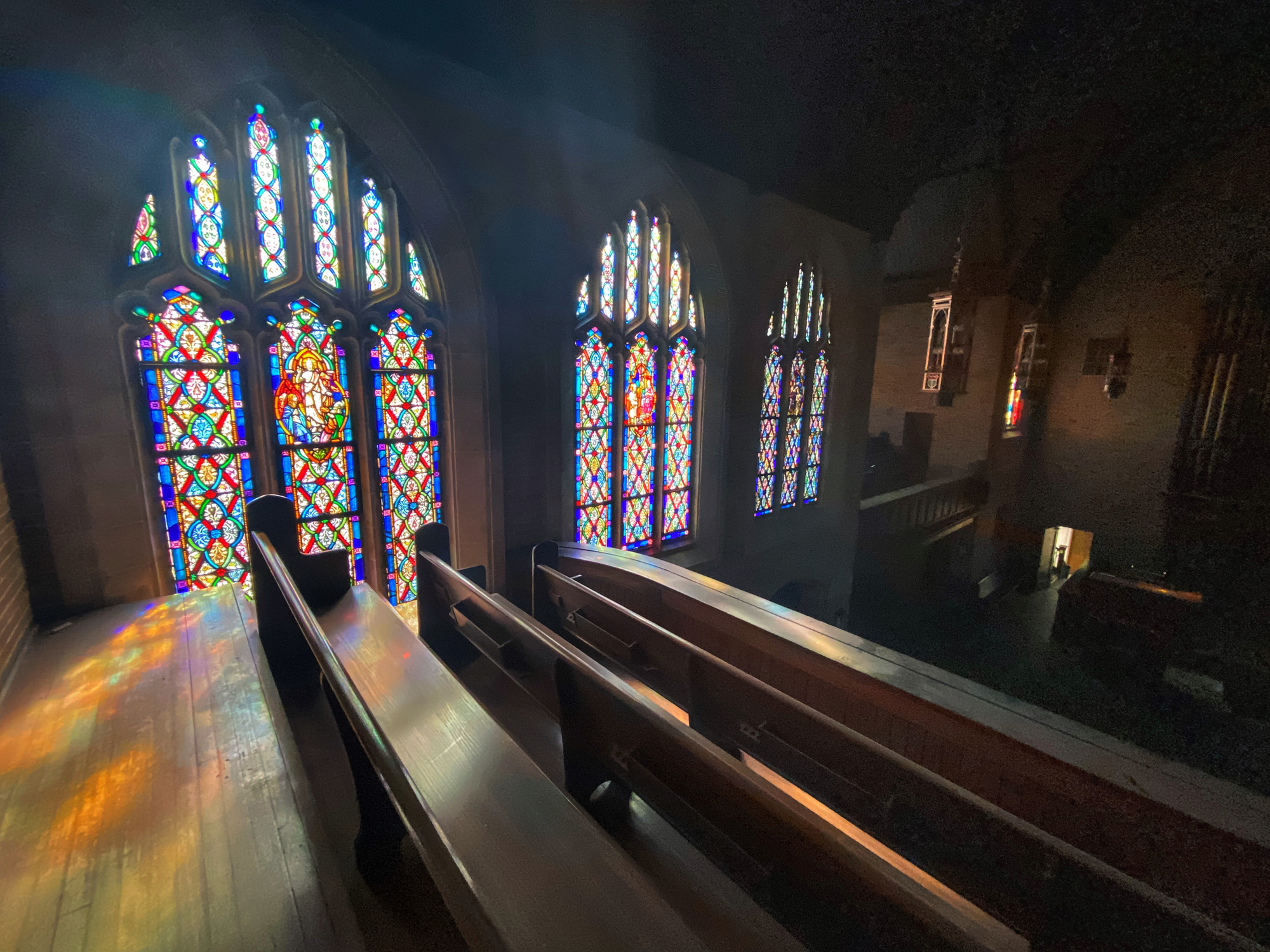 Interior of a church with colorful stained glass windows illuminating wooden benches