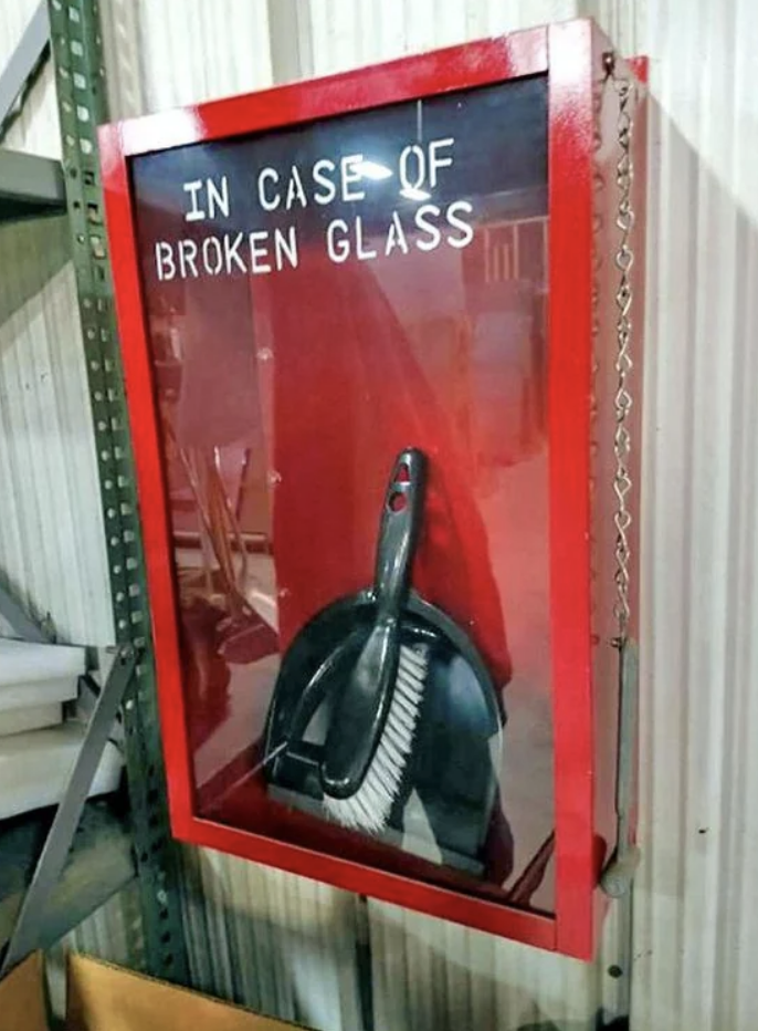 A red emergency case containing a dustpan and brush with the words &quot;IN CASE OF BROKEN GLASS&quot; on the front