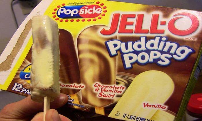 A person holds a Chocolate Vanilla Swirl Jell-O Popsicle pudding pop in front of its packaging box, which also shows Vanilla and Chocolate flavors