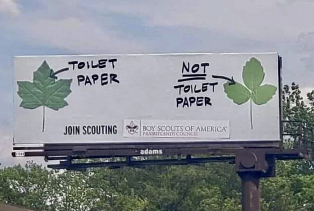 A billboard shows a comparison between two leaves: one labeled &quot;Toilet Paper&quot; and the other &quot;Not Toilet Paper,&quot; promoting the Boy Scouts of America