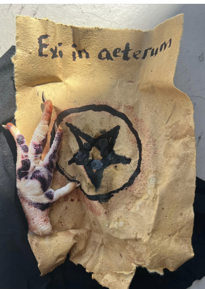 A parchment with &quot;Ex in aeternum&quot; written on it, featuring a pentagram and a severed, gory, clawed hand next to it