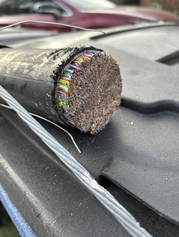 Close-up of a thick cable with many colorful wires inside, resting on a black surface