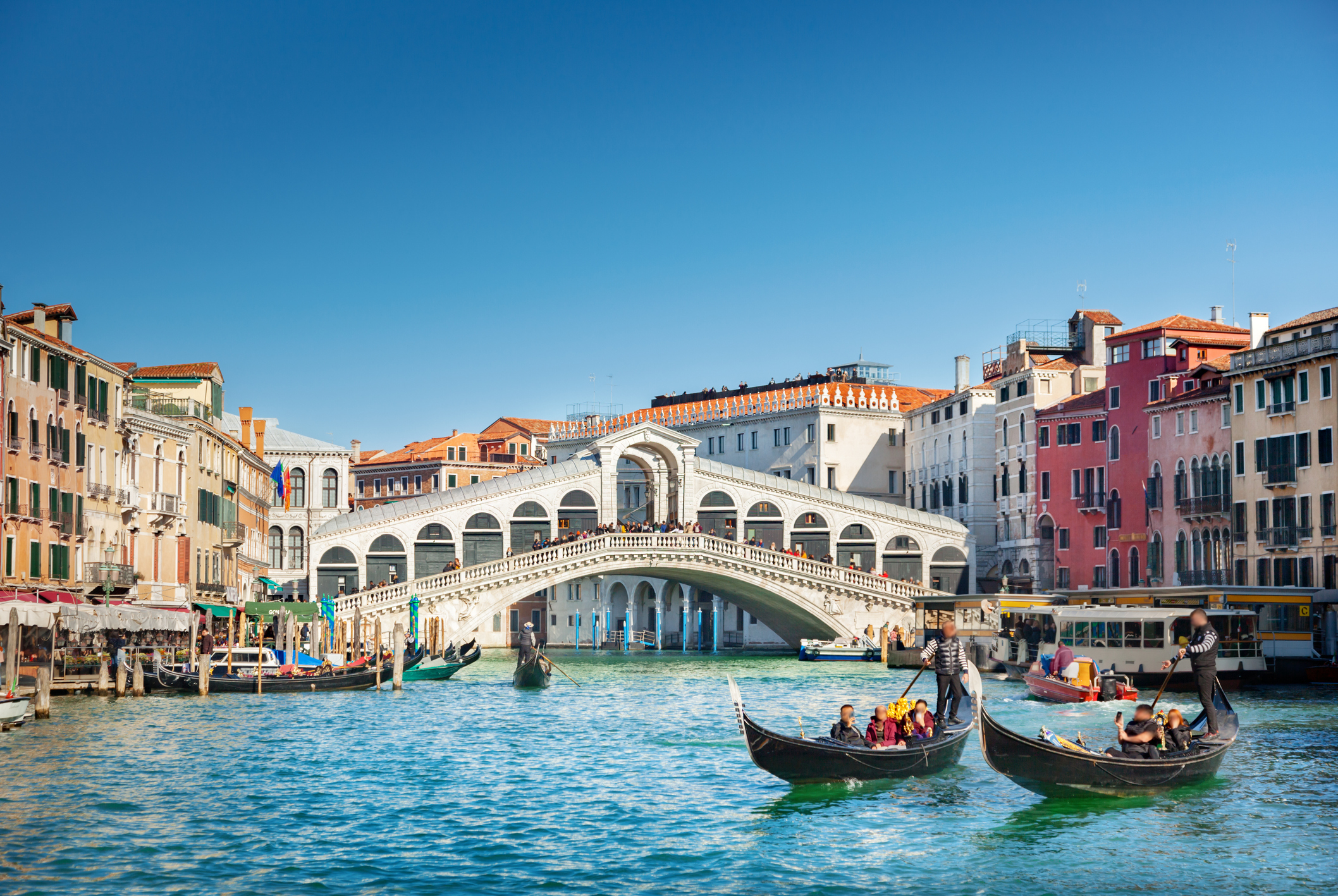 Gondolas on a canal in Venice, with the Rialto Bridge and surrounding buildings in the background