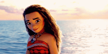 Moana, the animated character from the Disney movie &quot;Moana,&quot; is standing by the ocean, wearing a red patterned dress and a shell necklace.