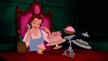 Belle enjoying various desserts at a table in a scene from &quot;Beauty and the Beast&quot;.