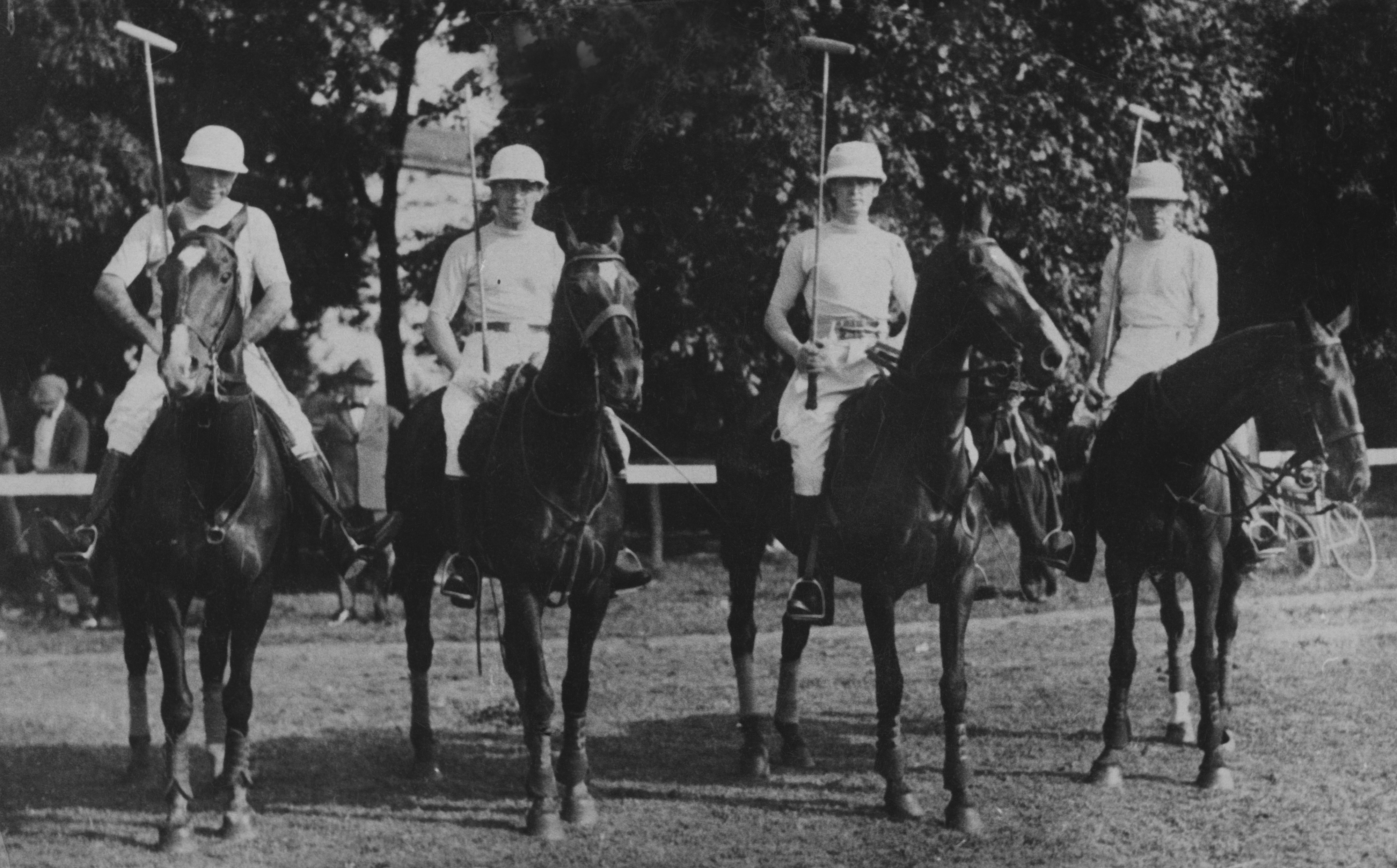 People on horseback ready to play polo, holding mallets and wearing helmets. Names of individuals are not provided