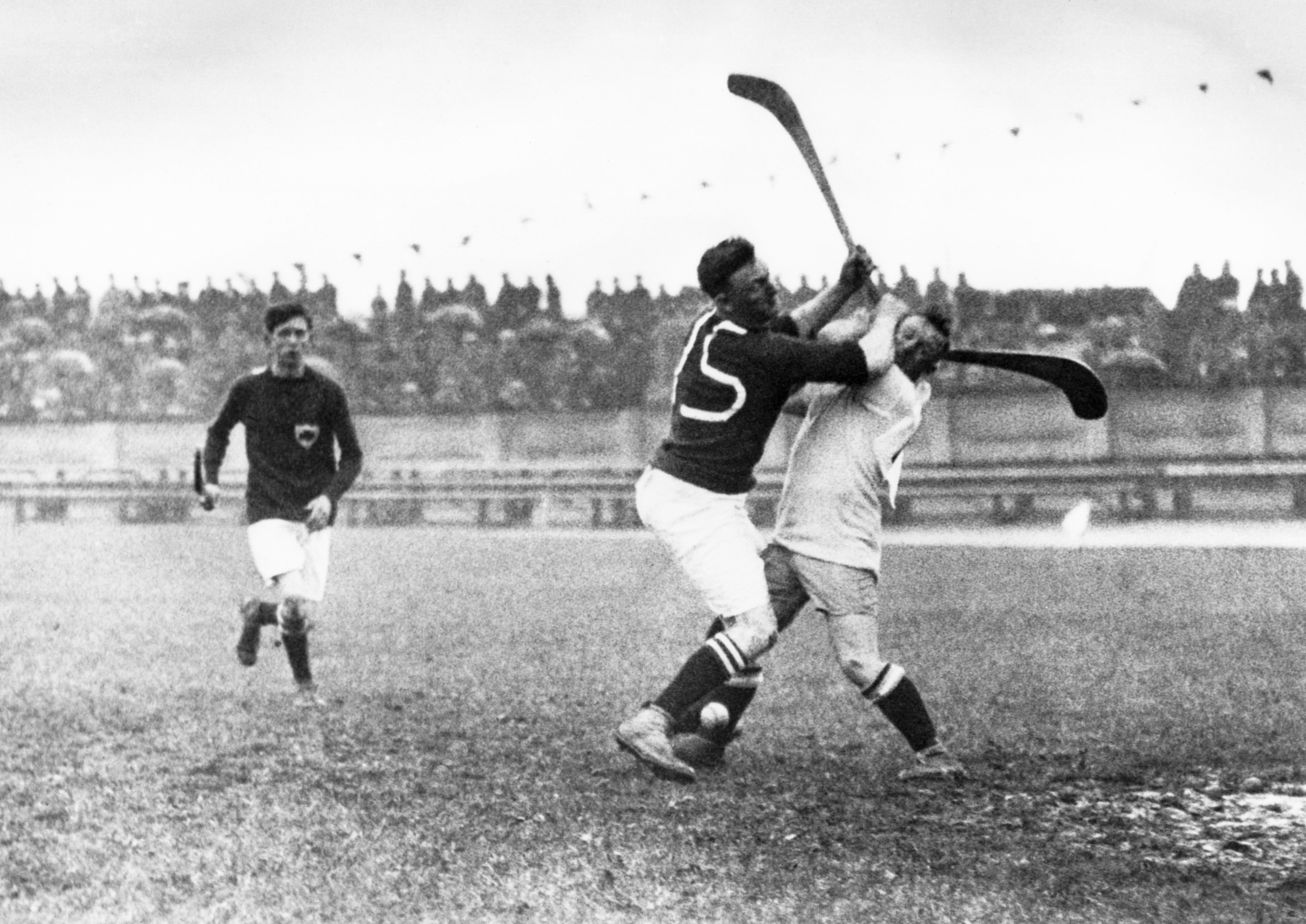 Vintage photo of a field hockey match where two players are clashing, with one player raising their stick over another&#x27;s head. Another player is in the background