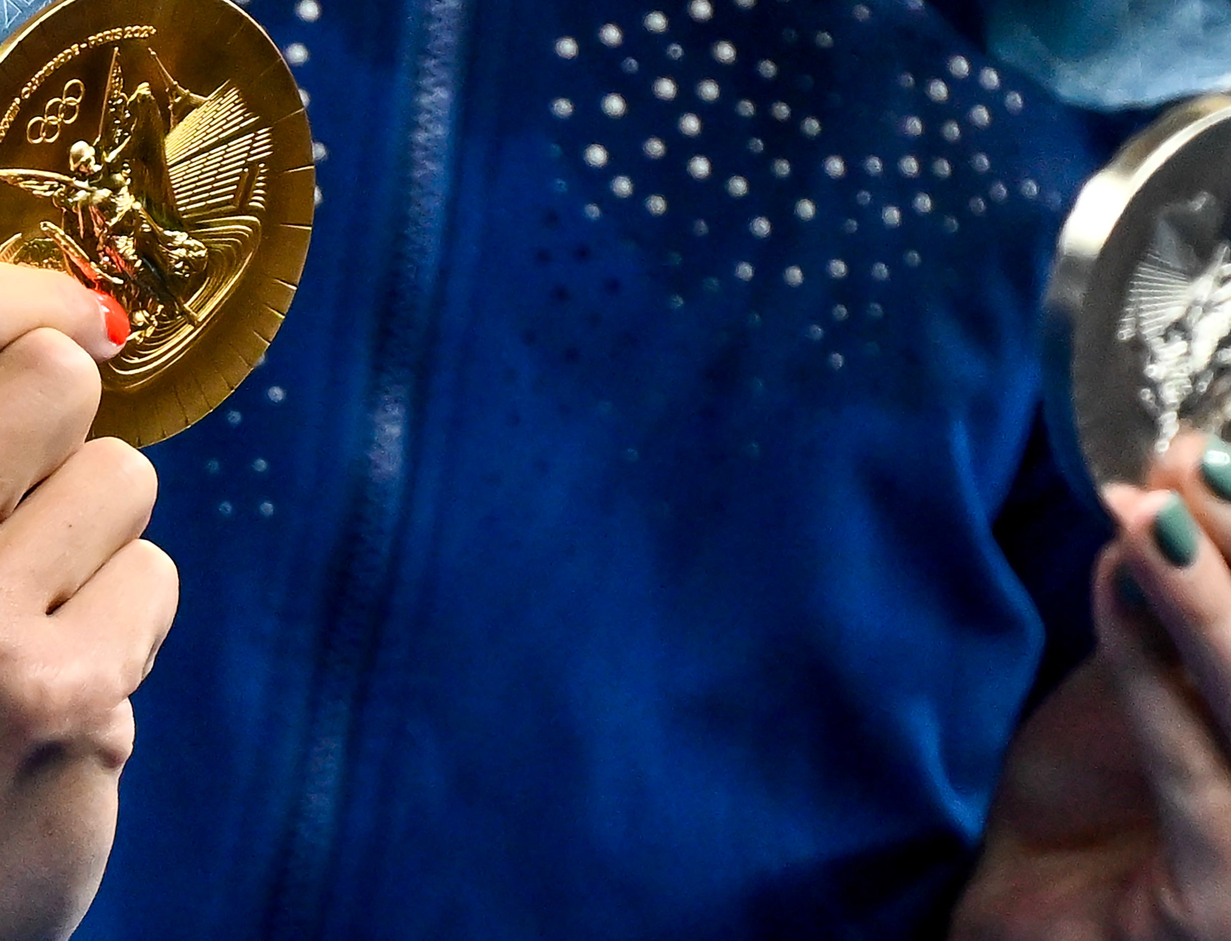 Close-up of a person&#x27;s hand holding an Olympic gold medal