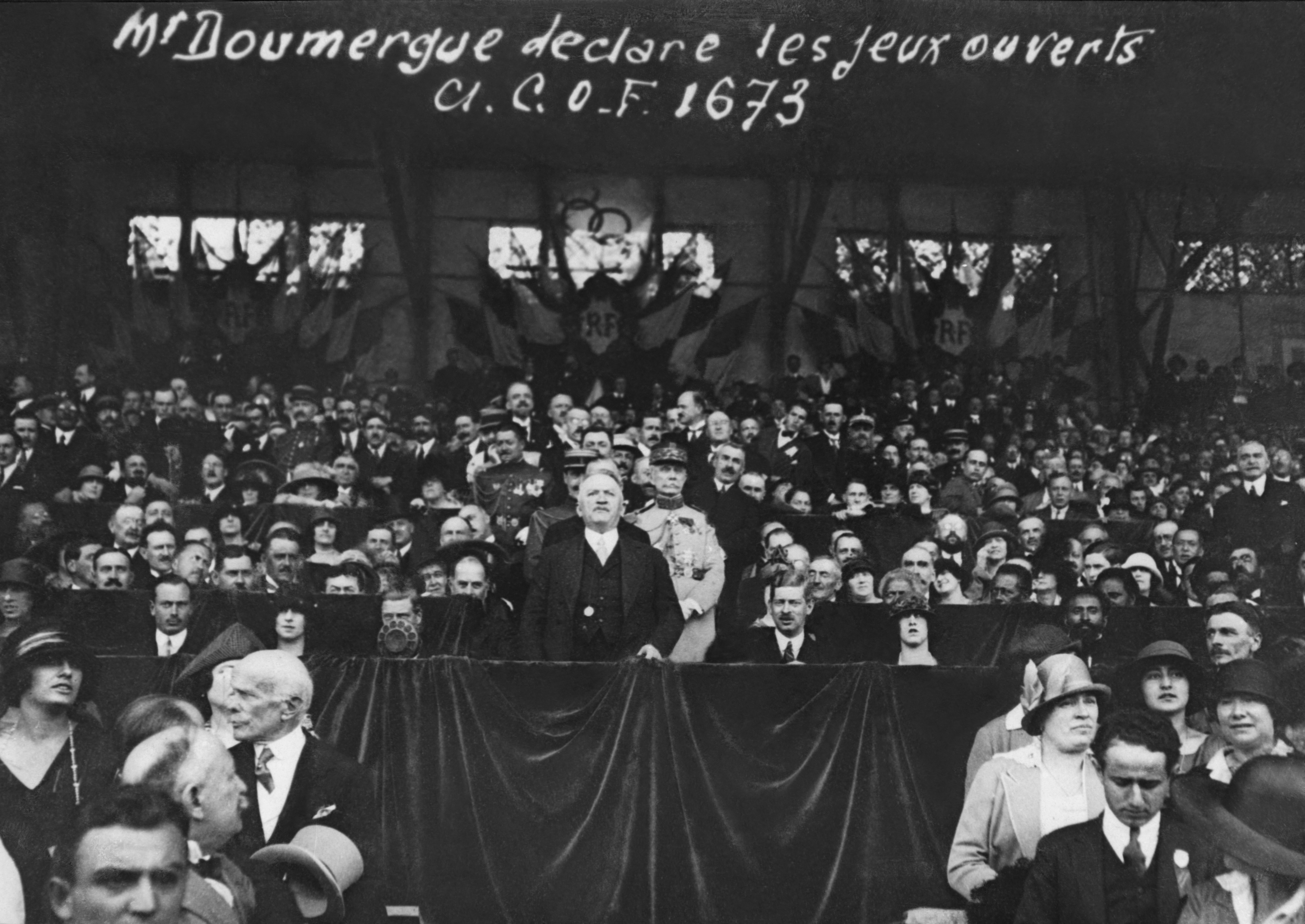 Gaston Doumergue declares the 1924 Paris Olympics open, standing before a crowd with banners and flags