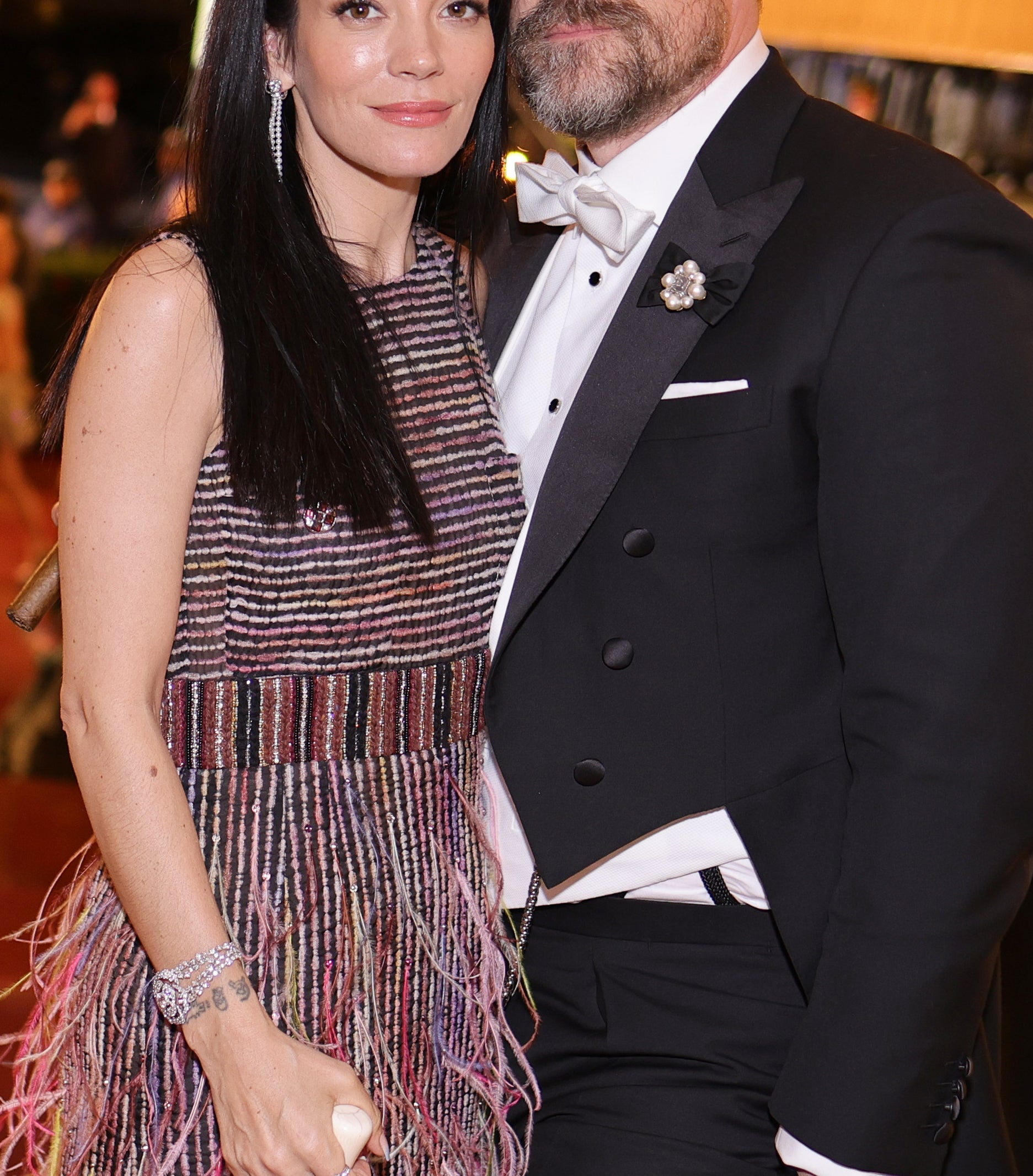 Lily Allen, wearing a fringed dress, and David Harbour, in a tuxedo, pose together at a formal event