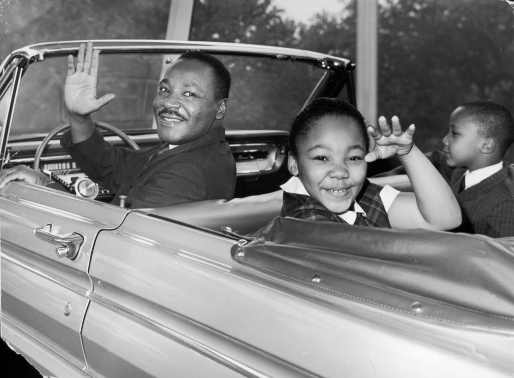 Martin Luther King Jr. waves from a convertible car with his daughter Yolanda King and son Martin Luther King III