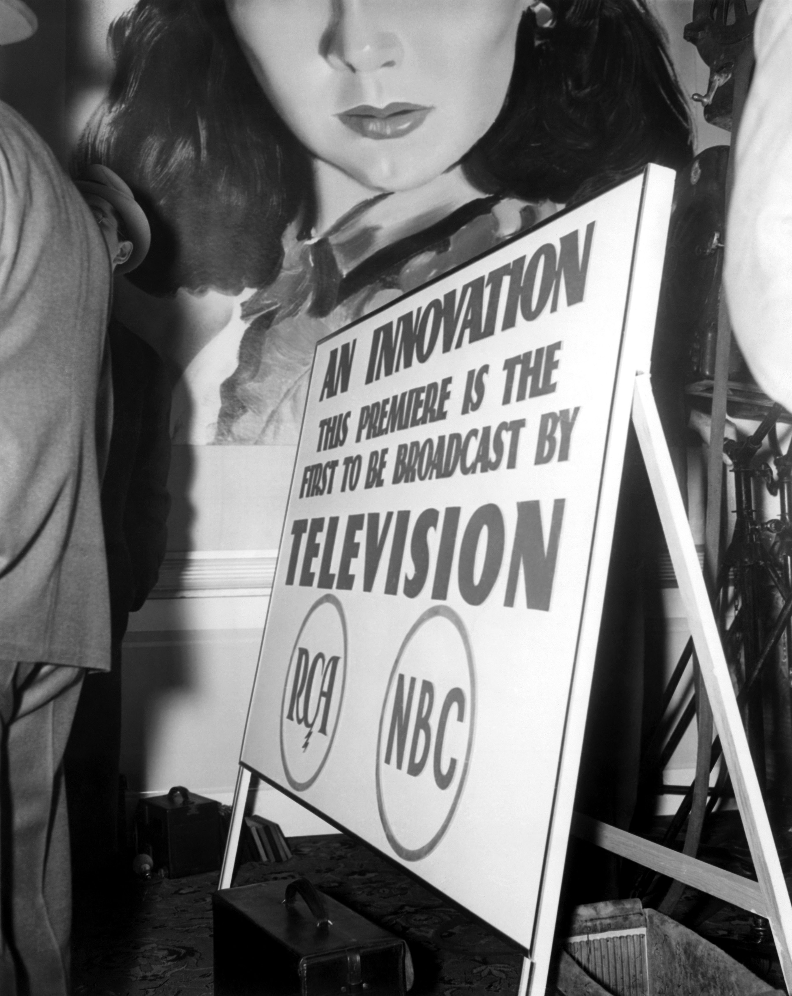 Poster with text: &quot;An innovation. This premiere is the first to be broadcast by television&quot; featuring RCA and NBC logos, and a drawing of a woman&#x27;s face