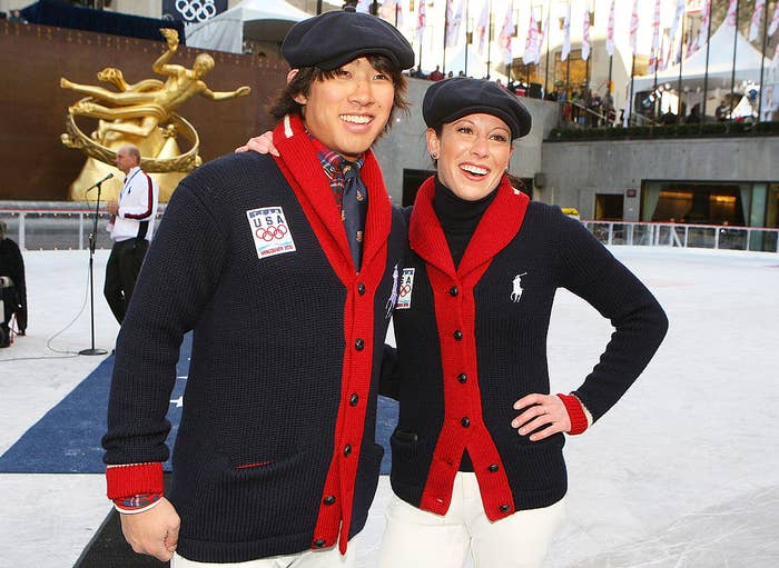 Two people wearing dark cardigans and newsboy caps at an ice skating rink