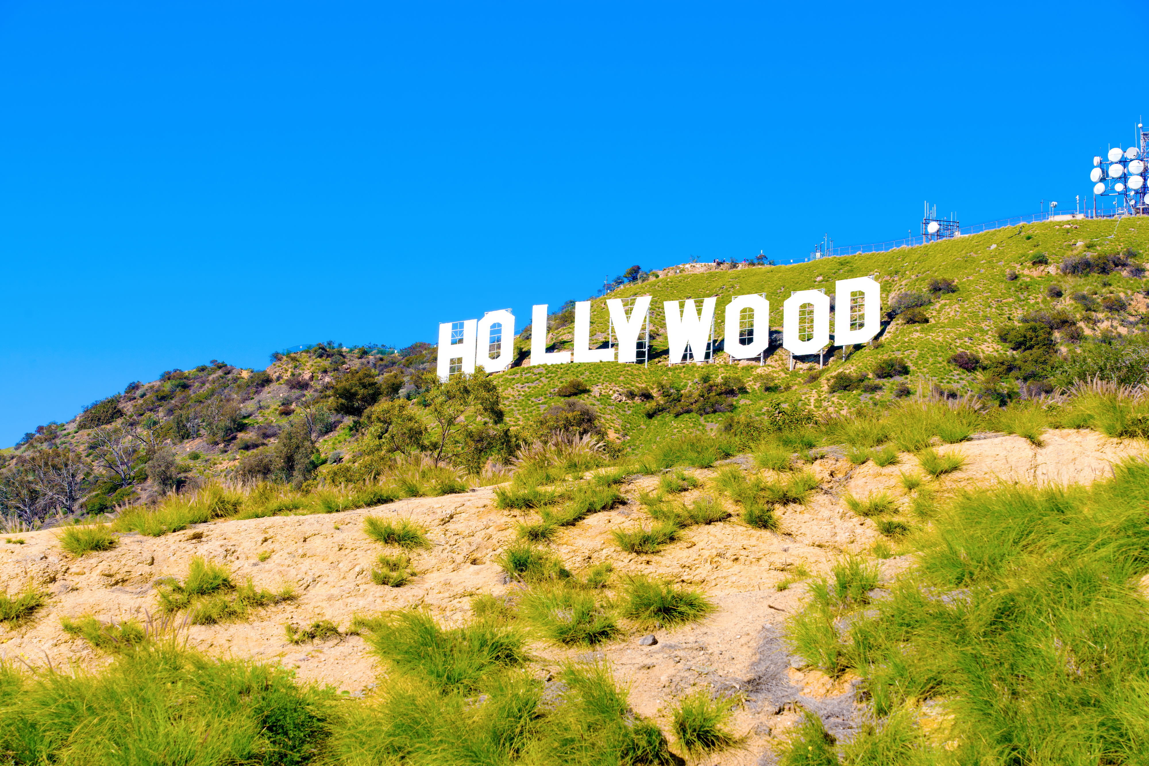 The image features the iconic Hollywood sign situated on a hillside, with clear sky above