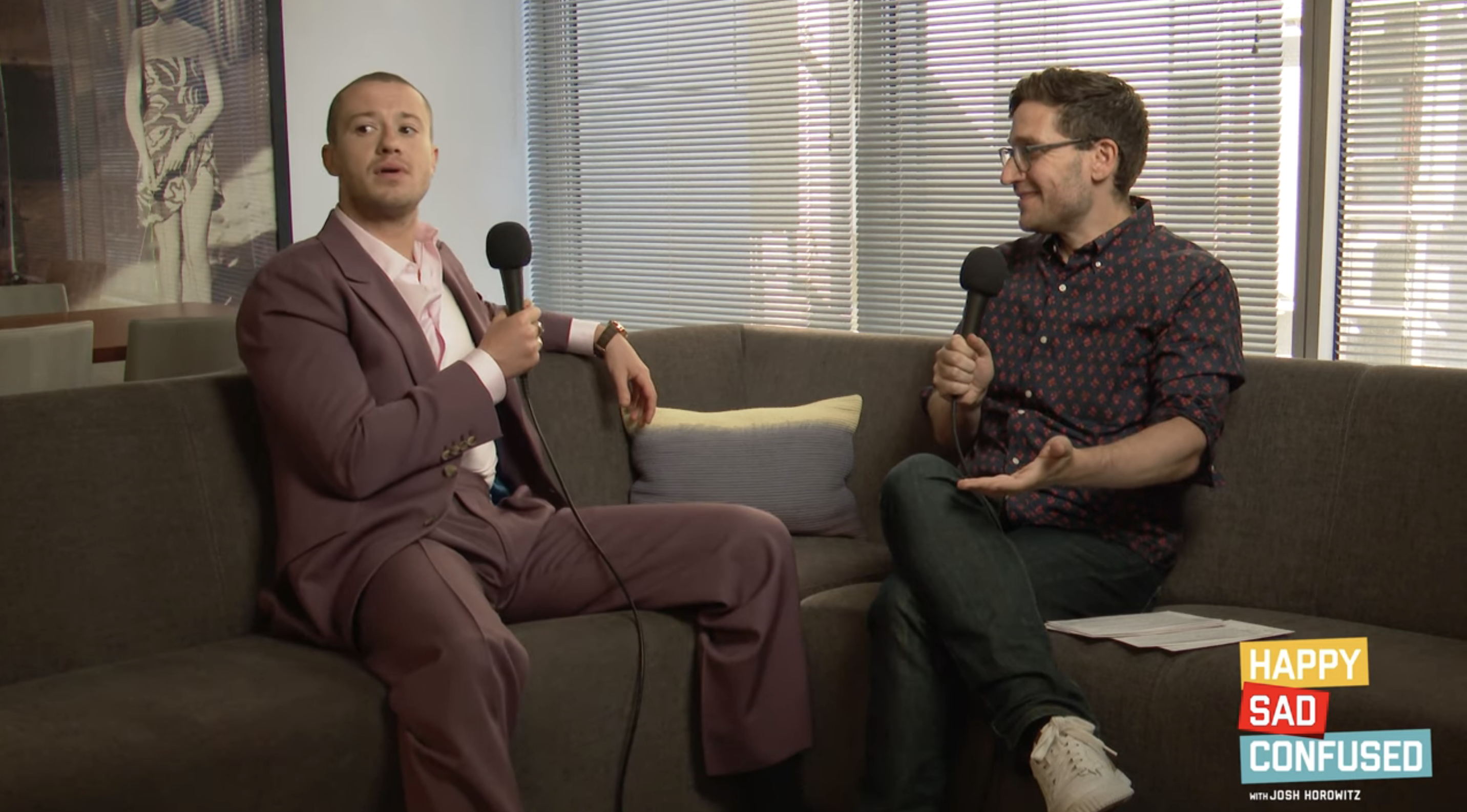 Josh Horowitz interviews Joseph Quinn on &quot;Happy Sad Confused.&quot; Both are sitting on a couch in an office setting