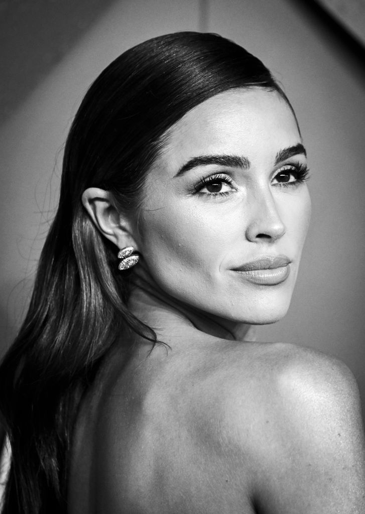 Olivia Culpo poses gracefully, showing off her elegant earrings and sleek hairstyle at a celebrity event
