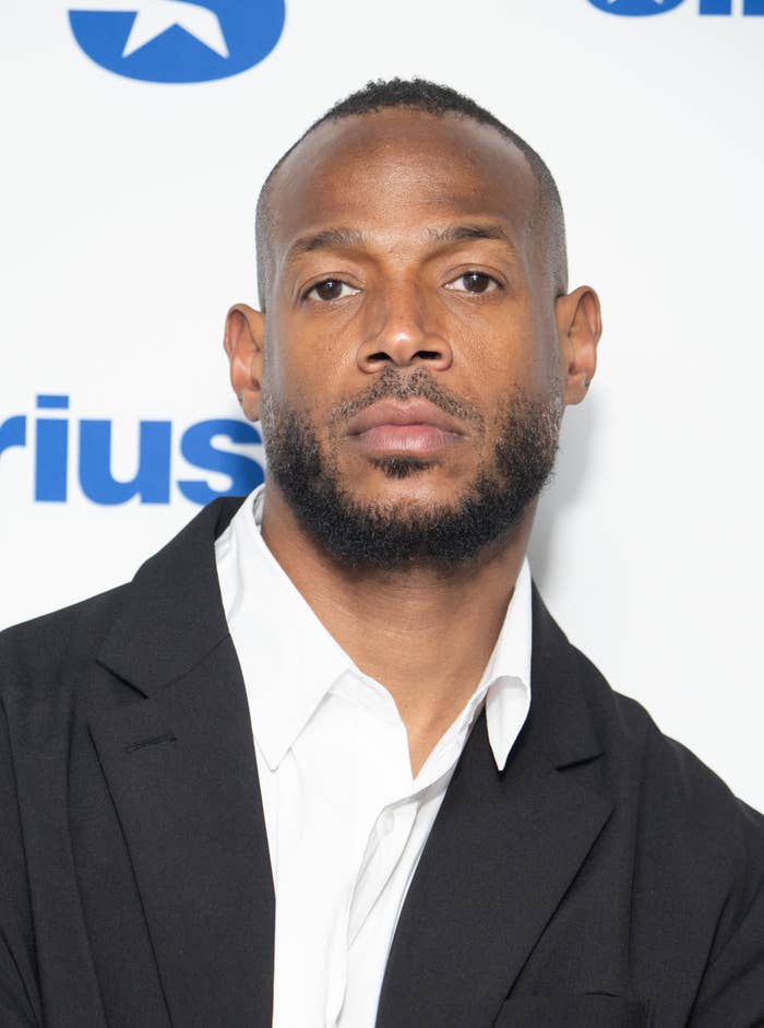 Marlon Wayans poses in a white shirt and black blazer at a SiriusXM event